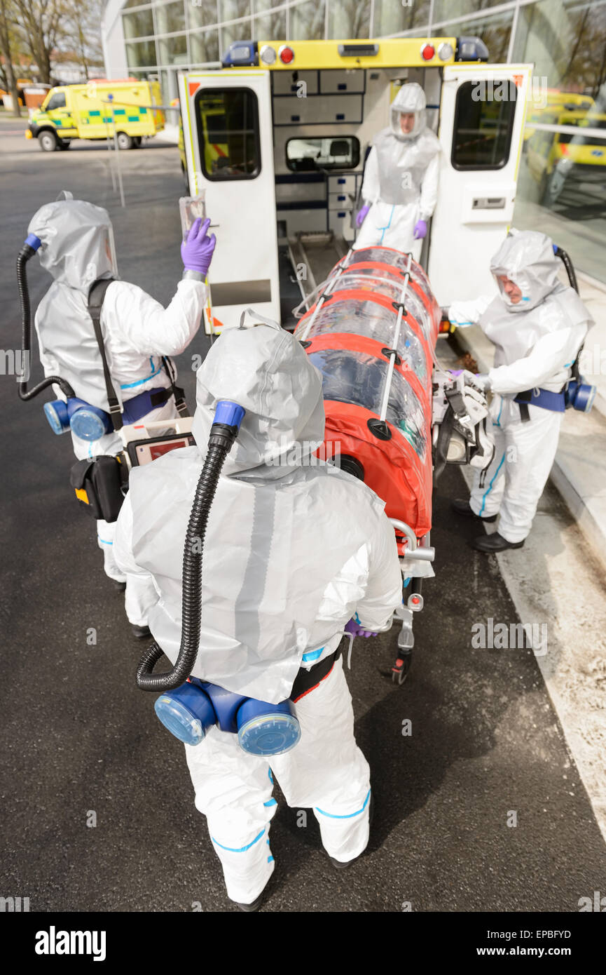 Biohazard team loading stretcher in ambulance Stock Photo