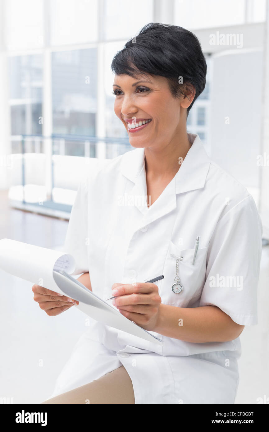 Smiling female doctor writing on clipboard Stock Photo - Alamy