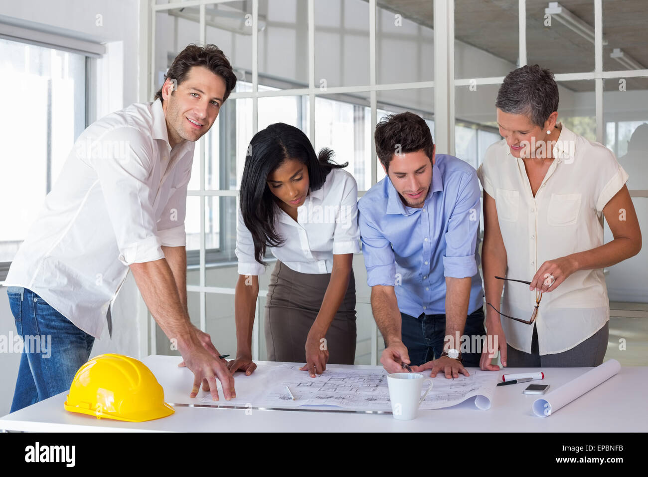 Team of architects going over blueprints with one smiling at camera ...