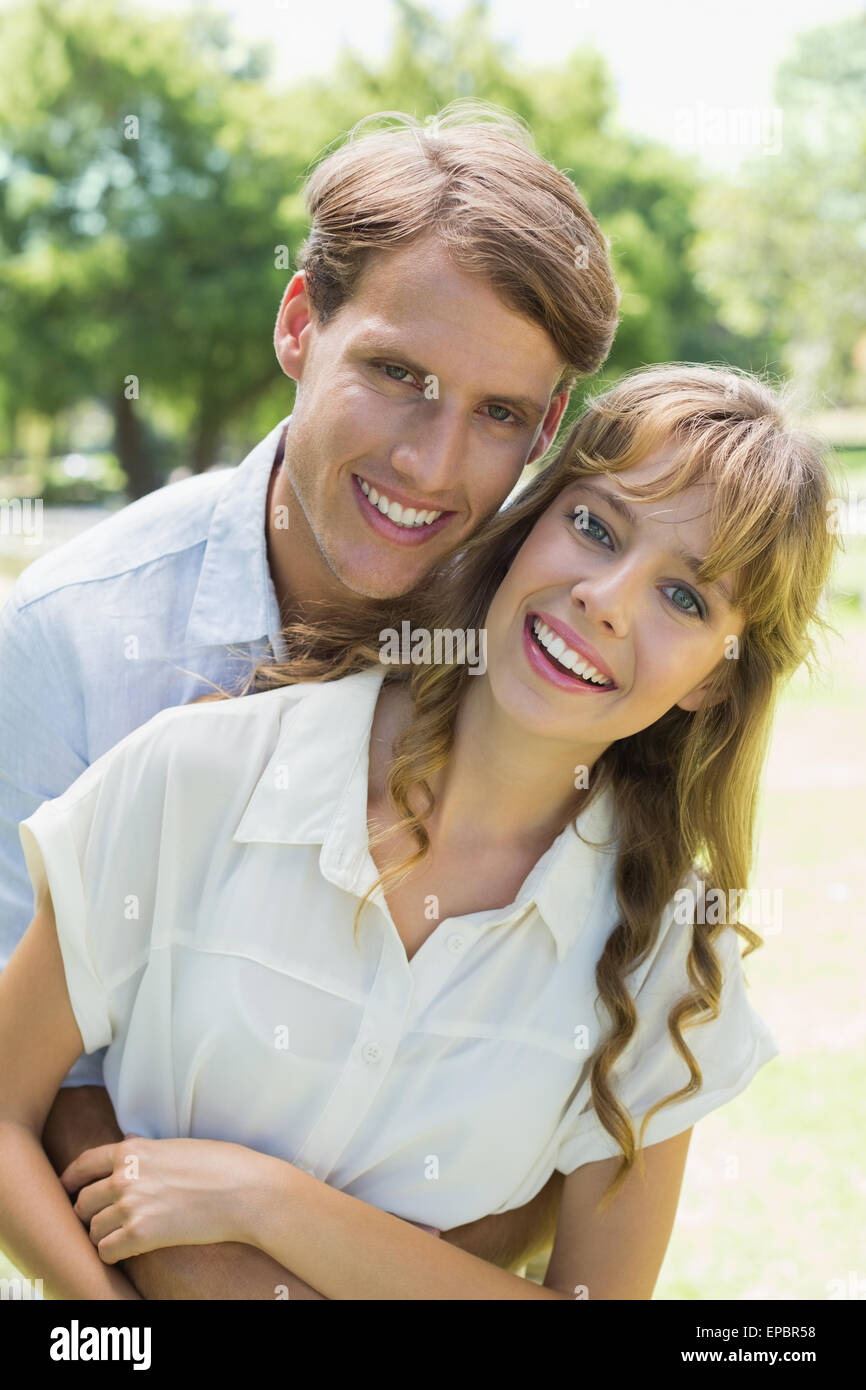 Attractive couple embracing and smiling at camera in park Stock Photo
