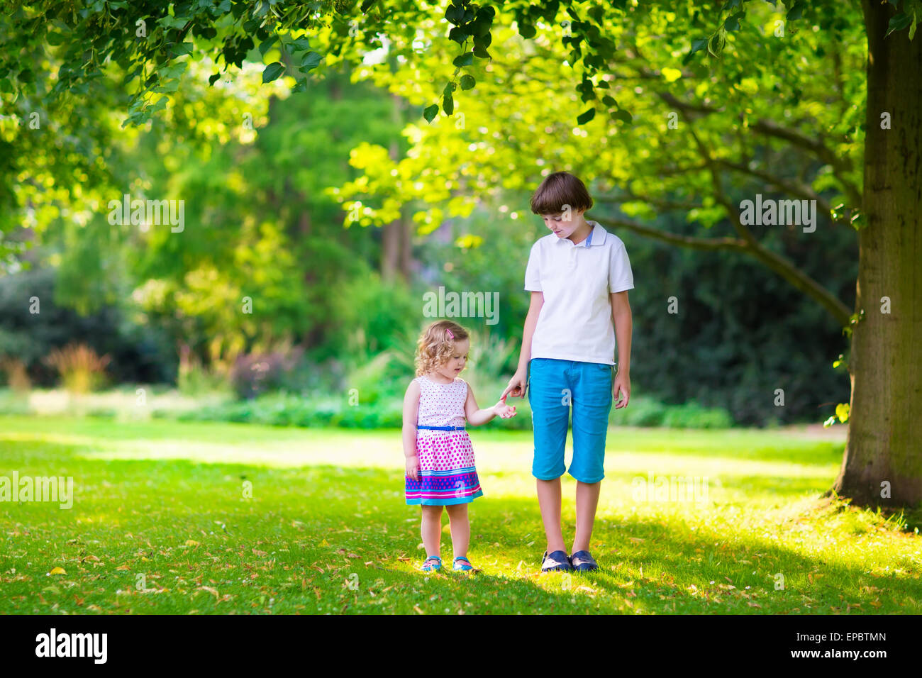 Children playing in a park. Kids holding hands walking in the forest running together playing in park Stock Photo