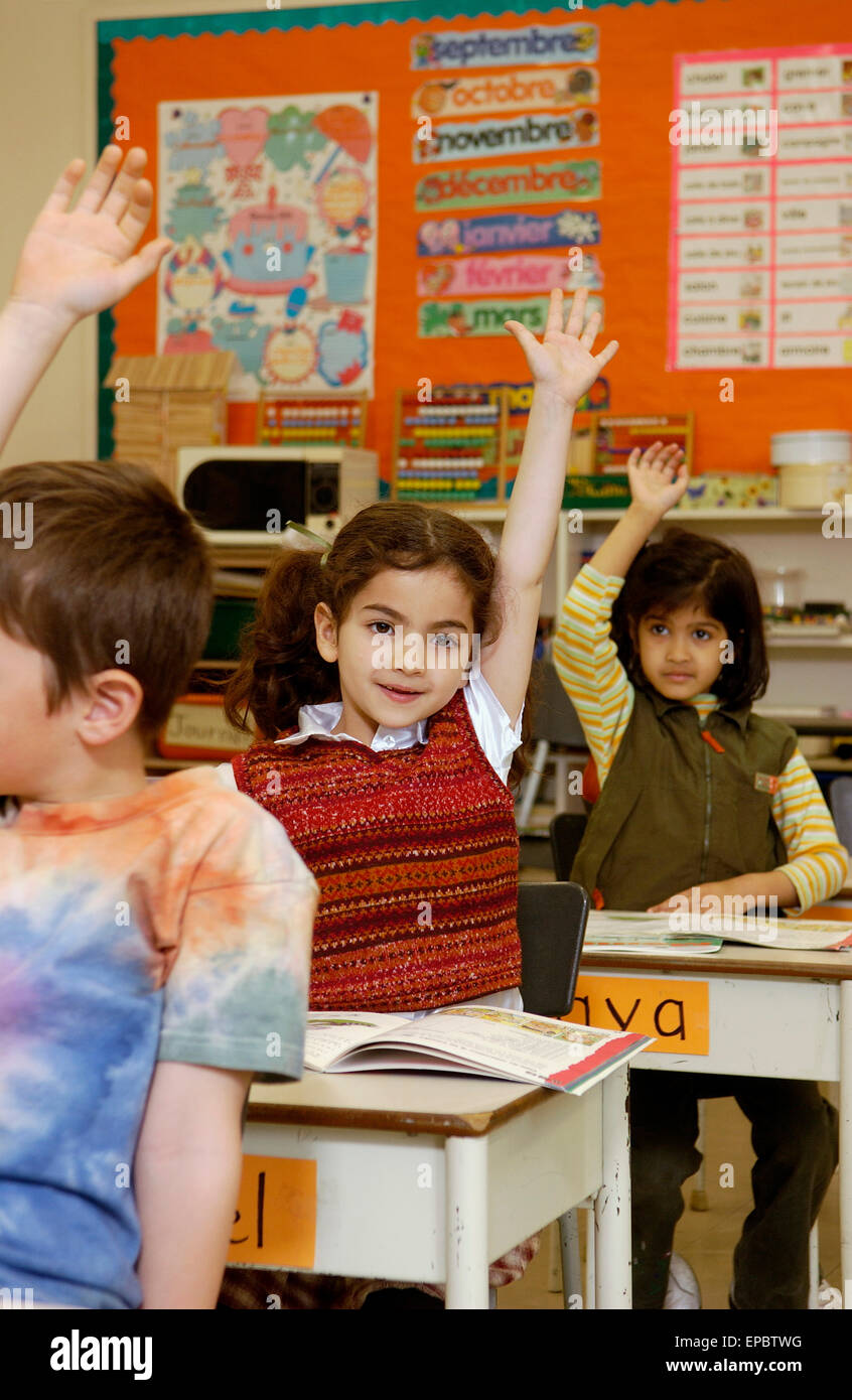 Grade 2 students raising their hands in classroom Stock Photo