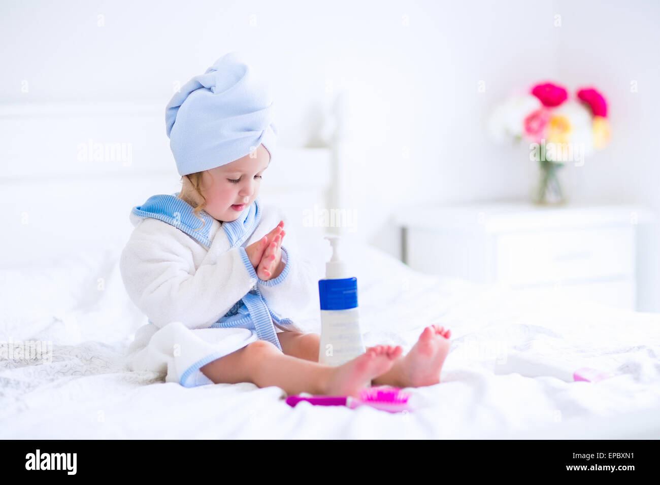 Cute curly little girl in a white and blue bathrobe with a towel over ...