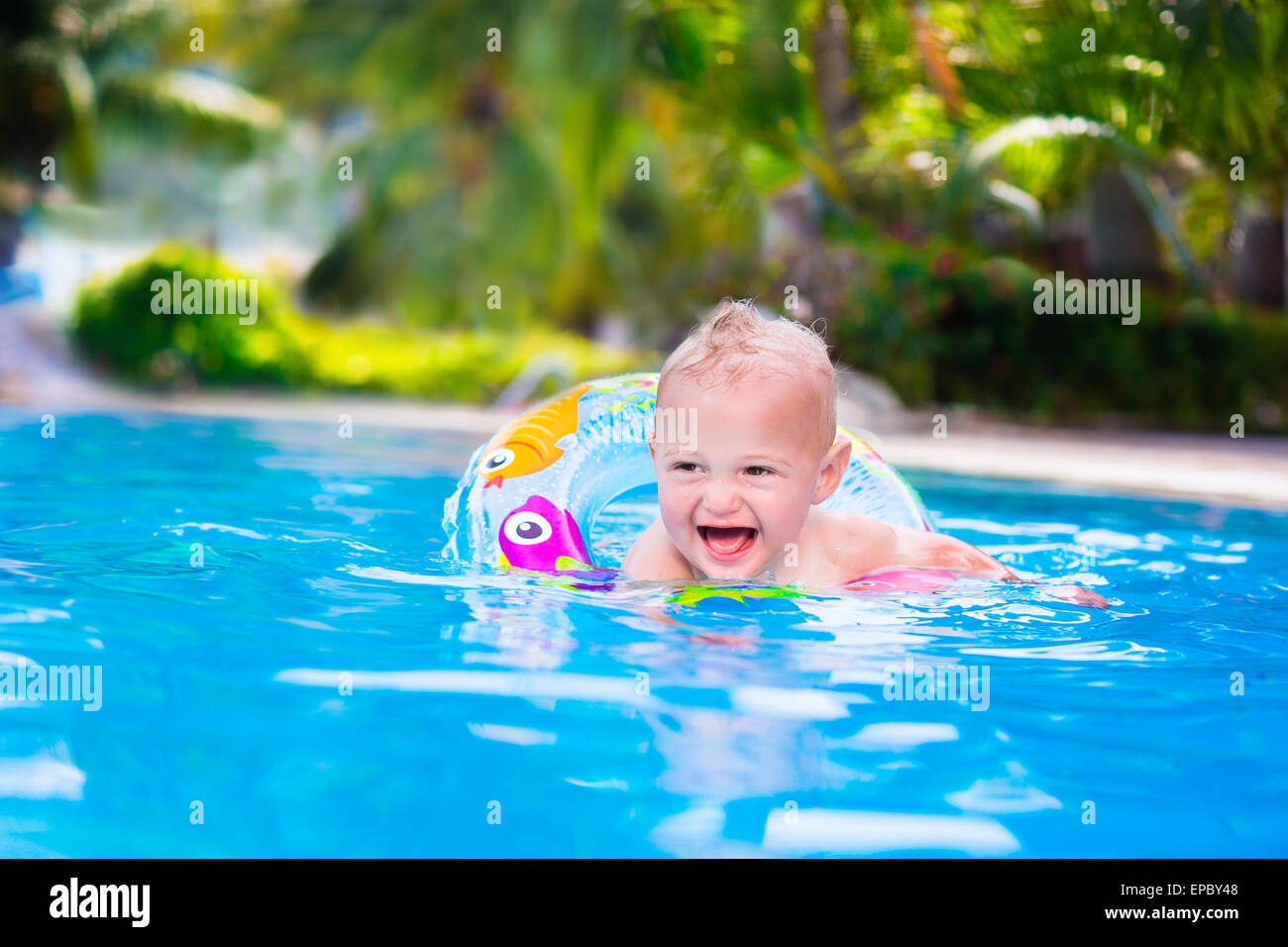Adorable little baby boy having fun in a swimming pool in a beautiful