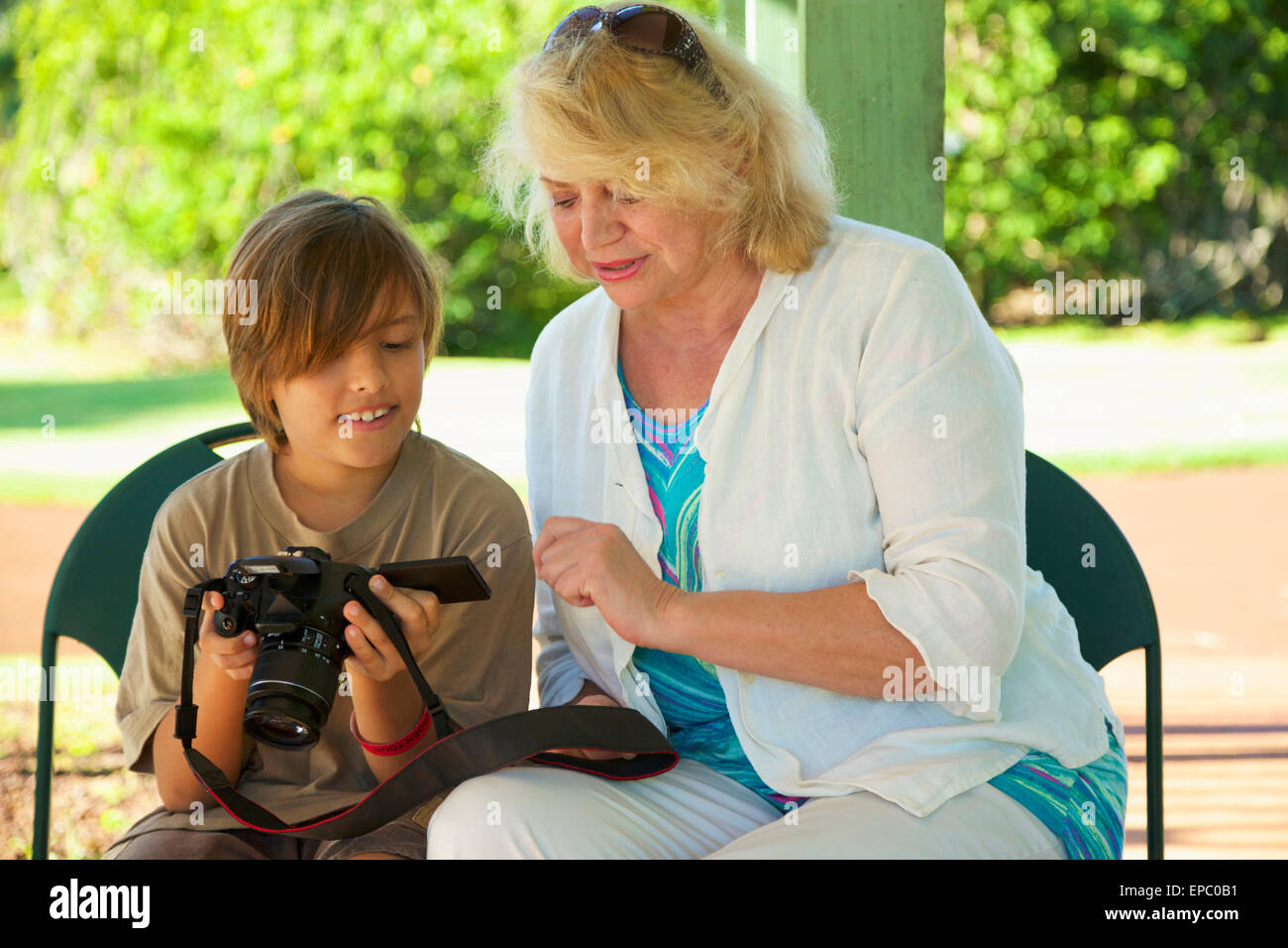 A grandmother and grandson look at pictures on a digital camera screen, National Tropical Botanical Garden; Kauai, Hawaii, USA Stock Photo