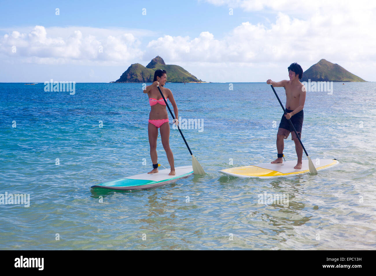 japanese couple on stand up paddleboards in hawaii Stock Photo