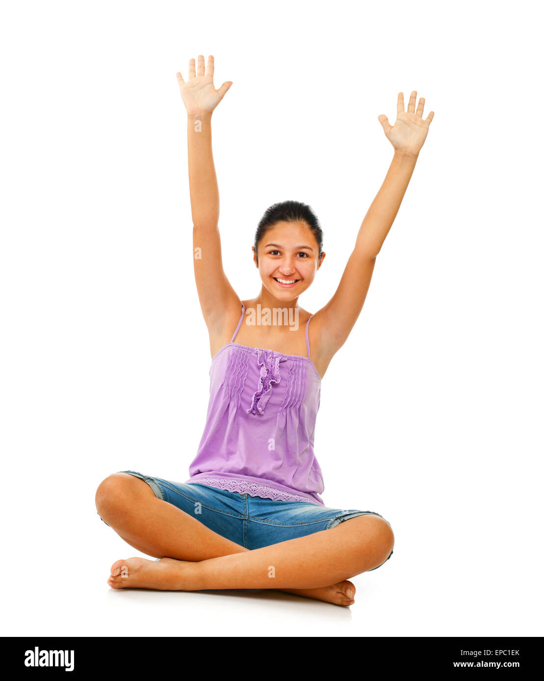 Sitting teenage girl while rejoices with arms up on white background Stock Photo