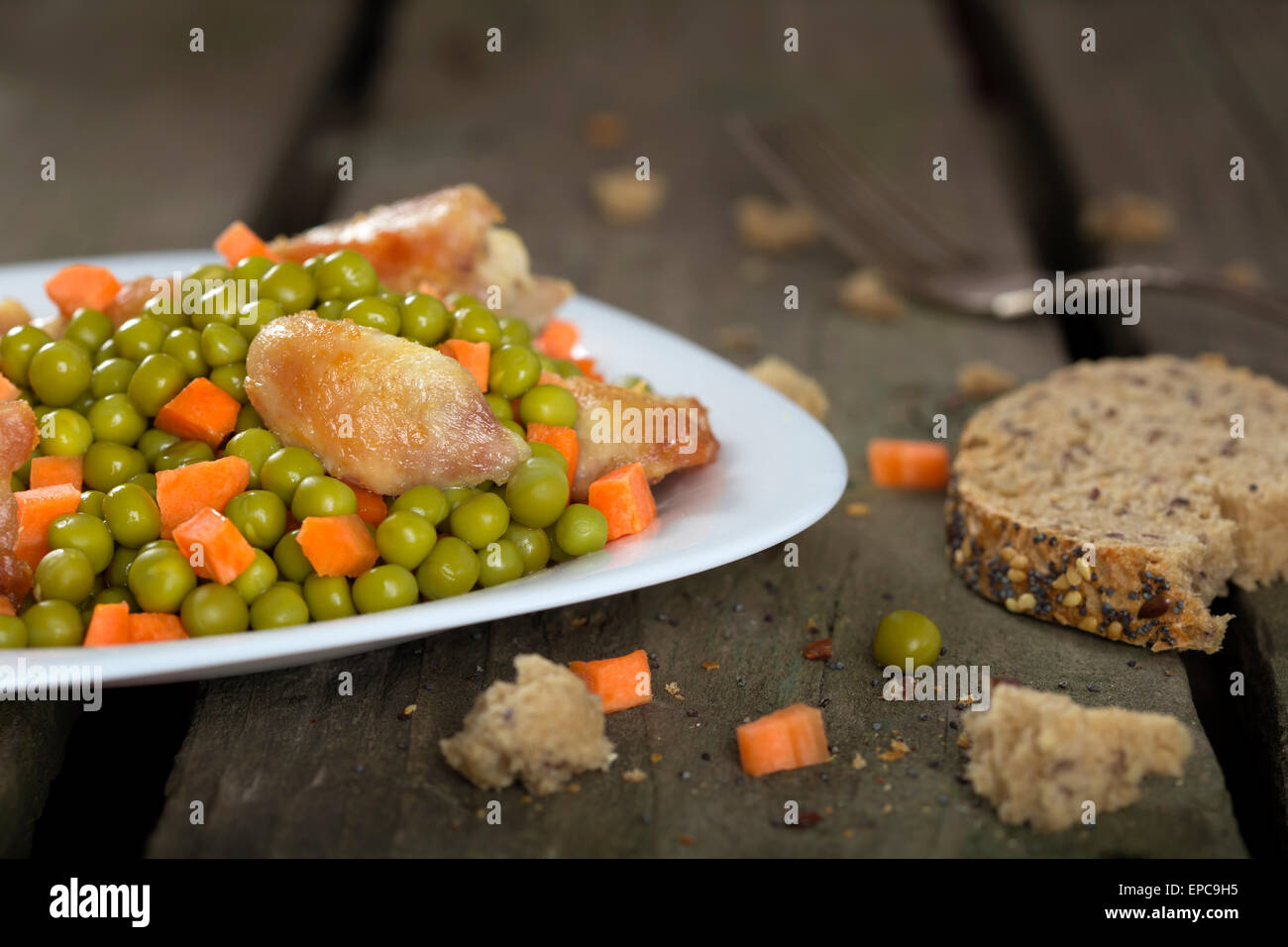 Chicken stew with carrots and green peas over wood rustic background Stock Photo