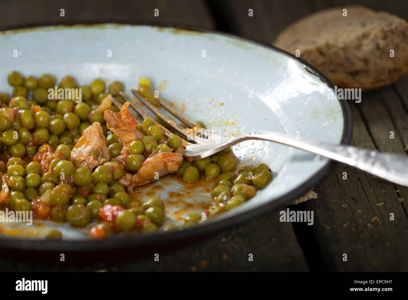 Eating chicken stew with carrots and green peas over wood rustic background Stock Photo