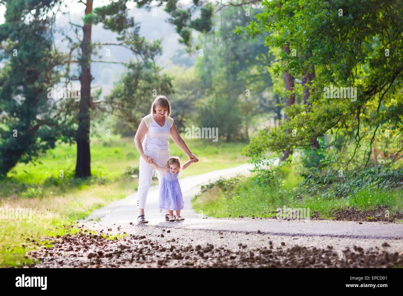 Happy active woman playing with a cute little child, adorable toddler girl in blue dress, having fun together enjoying hiking Stock Photo