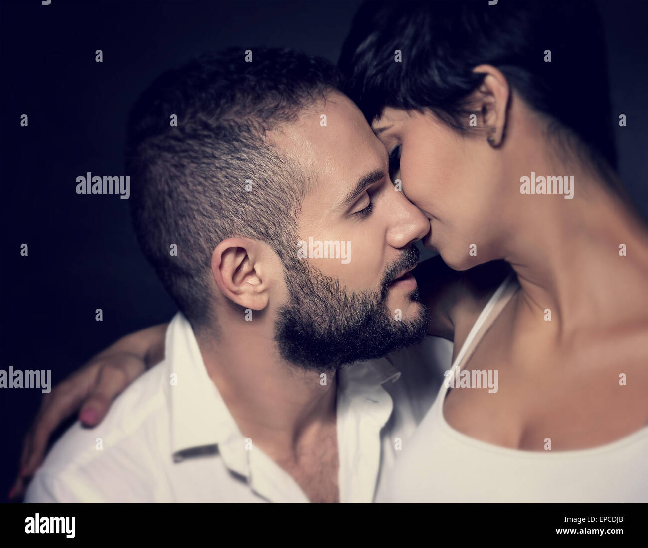 Closeup portrait of gentle loving couple kissing isolated on black background, enjoying romantic relationship Stock Photo