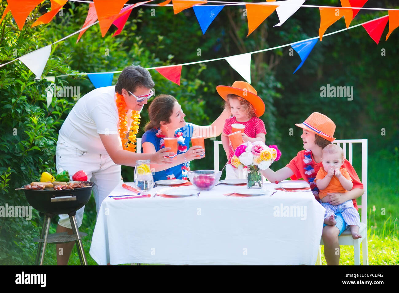 Happy big Dutch family with kids celebrating a national holiday or sport victory having fun at a grill party in a garden Stock Photo