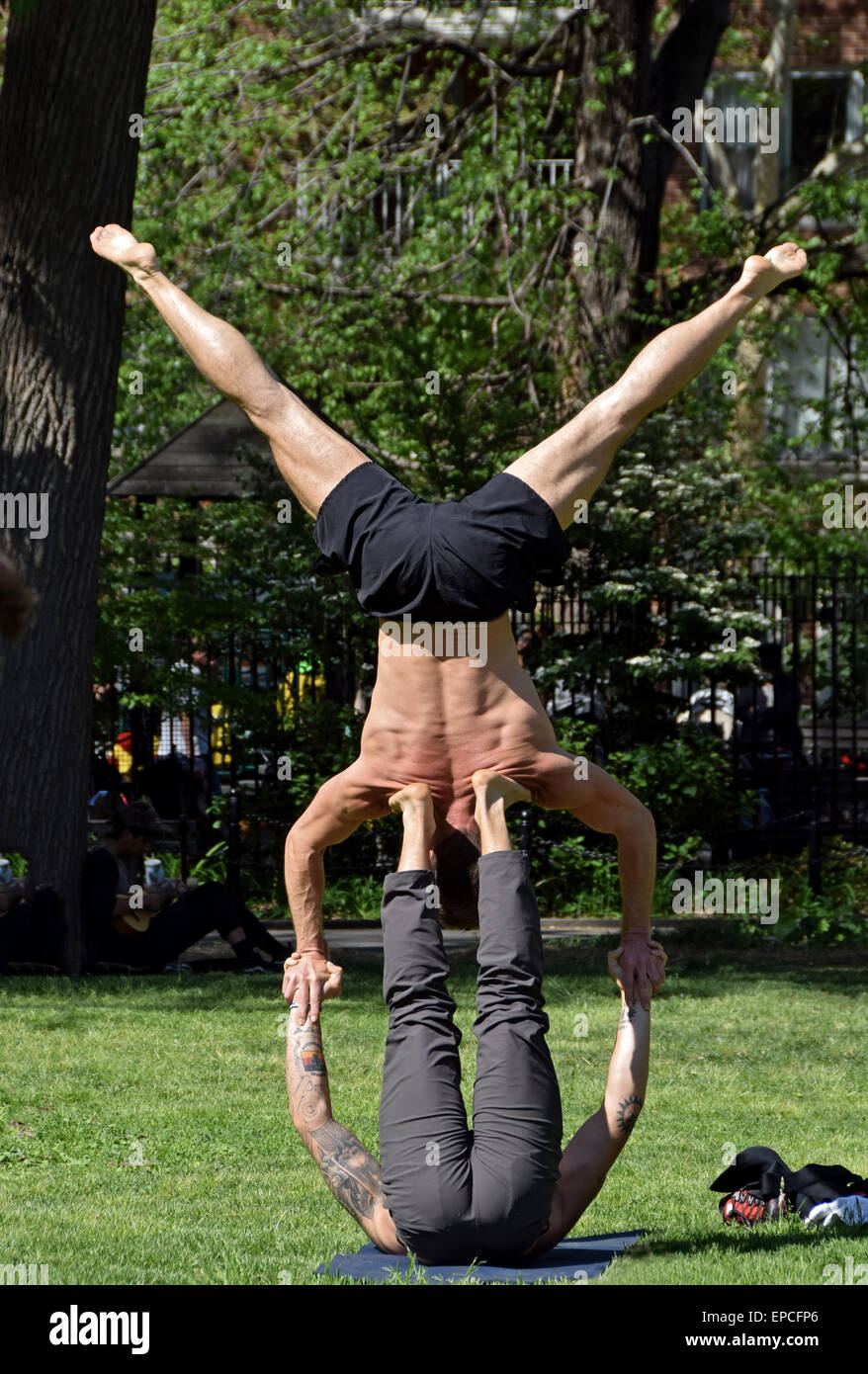 Two athletic fit men do acro yoga exercises in Washington Square Park