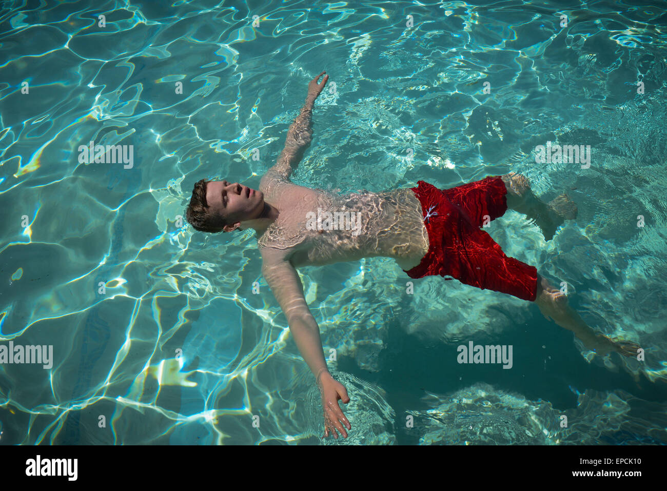 A teenage boy floats on his back in a swimming pool at Pells Pool, the oldest freshwater outdoor public swimming pool in the UK, in Lewes, East Sussex, England. Stock Photo