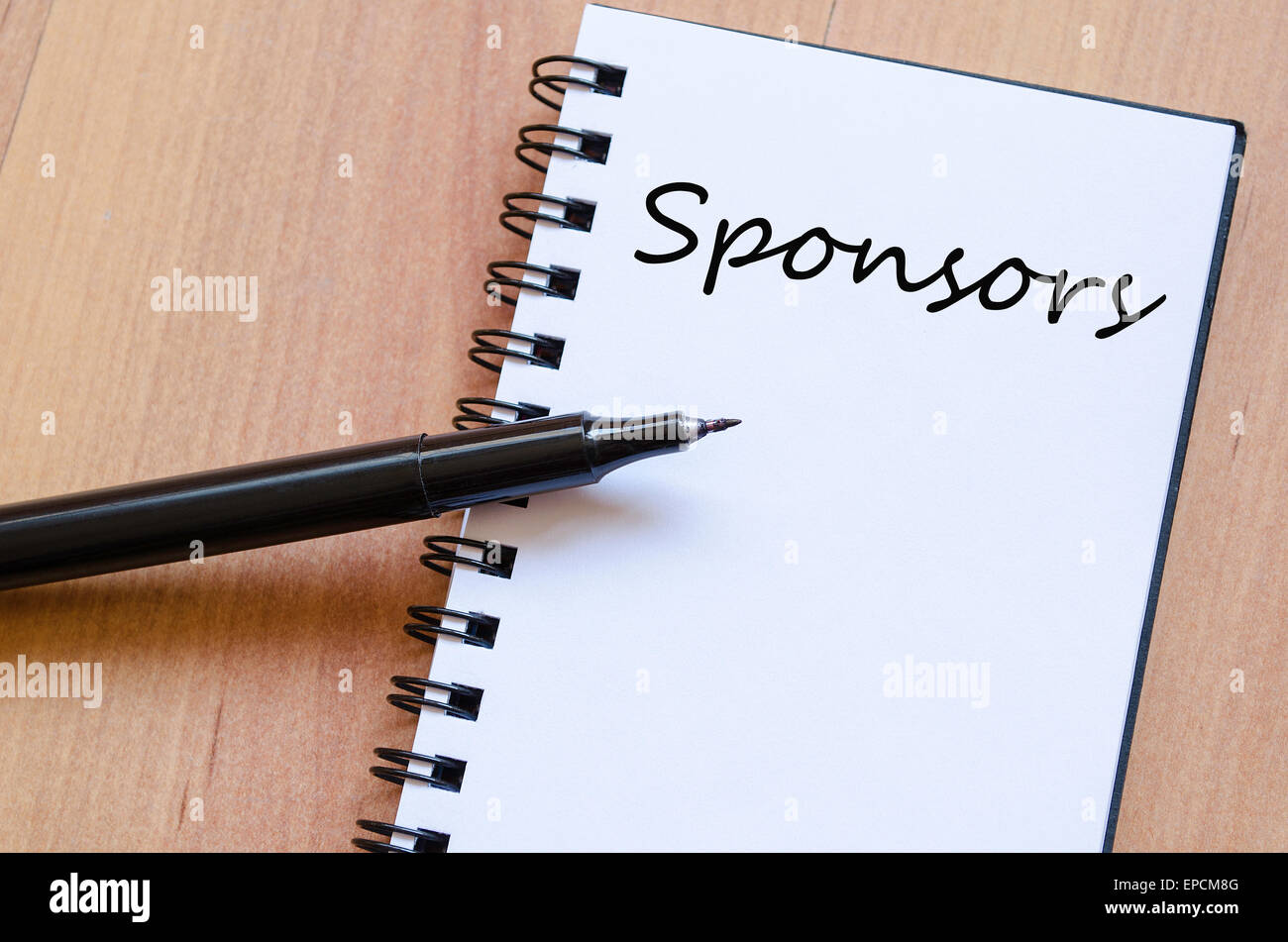 White notepad and ink pen on the wooden desk Sponsors Concept Stock Photo