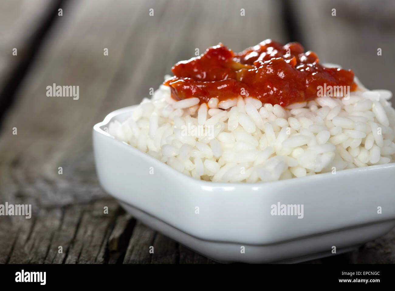 Bowl full of rice and tomato sauce over wooden background Stock Photo