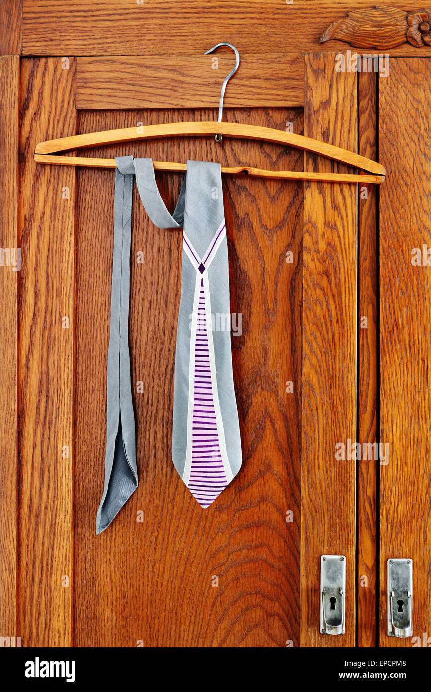 Vintage necktie hangs on a hanger on antique wardrobe Stock Photo
