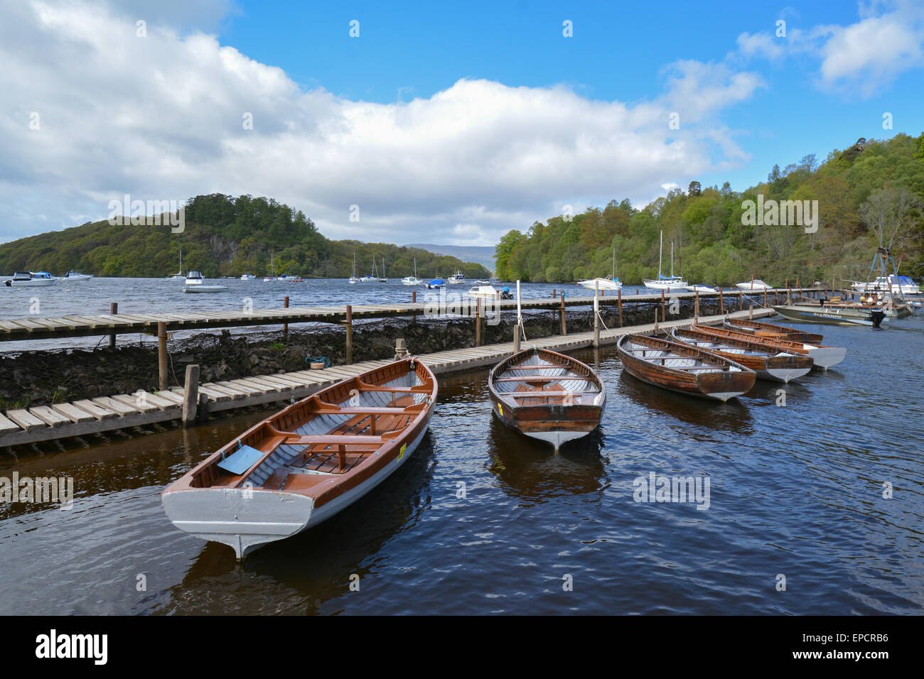 boats moored along the pier at Balmaha, Loch Lomond, Scotland with the tiny island of Inchcailloch behind (left) Stock Photo