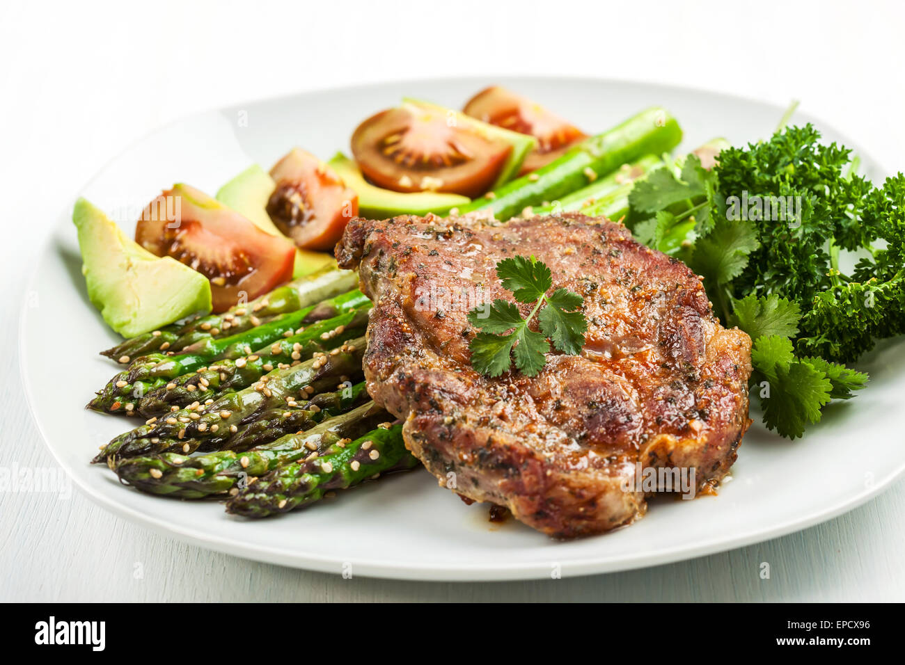 Glazed green asparagus with sesame seeds and grilled pork chop Stock Photo