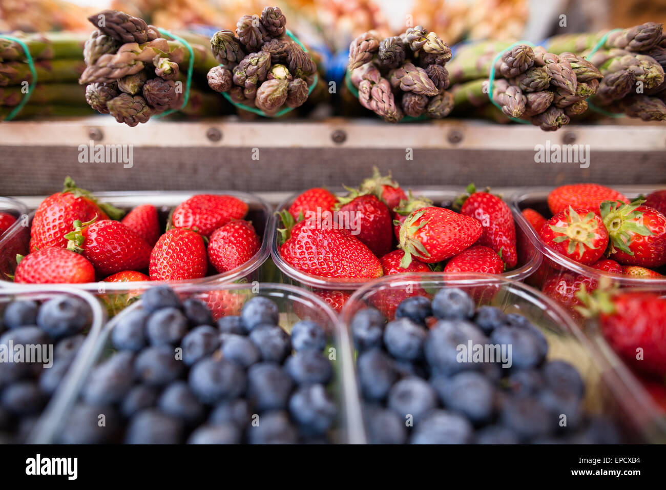 Beautiful fresh, ripe and delicious strawberries, blueberries and asparagus on a market stall Stock Photo