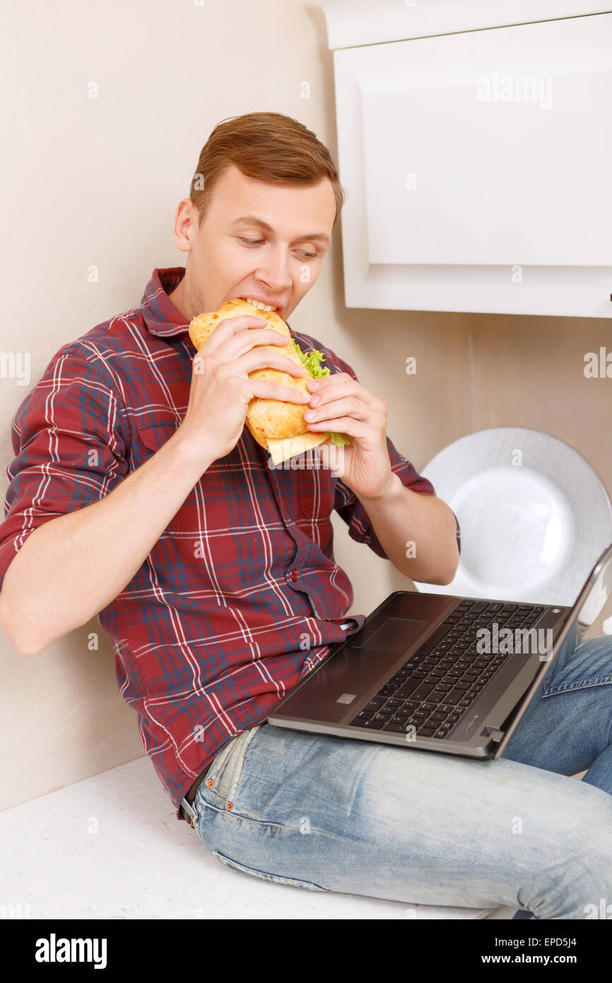 Man eating sandwich and holding notebook Stock Photo - Alamy