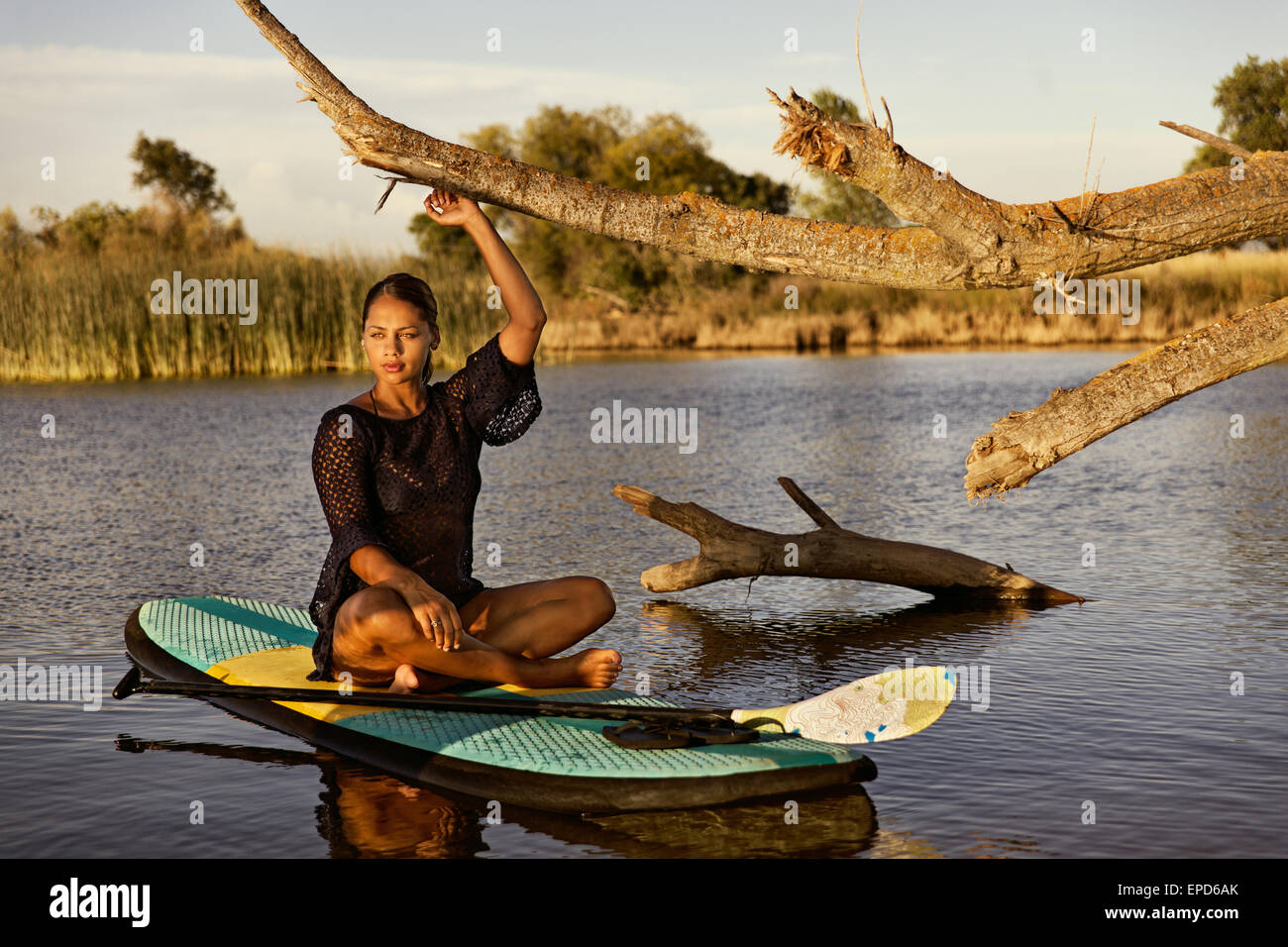 A young, attractive woman relaxing on a paddle board on a small lake in Northern California. Stock Photo