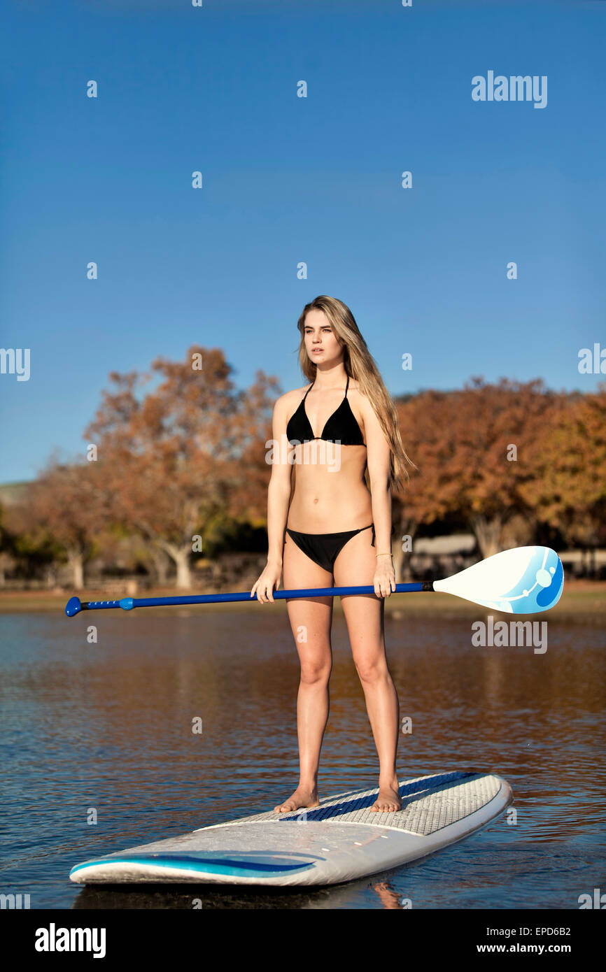 A young, fit woman in a bikini on a paddle board enjoying a Fall SUP  session on a small lake in Northern California Stock Photo - Alamy