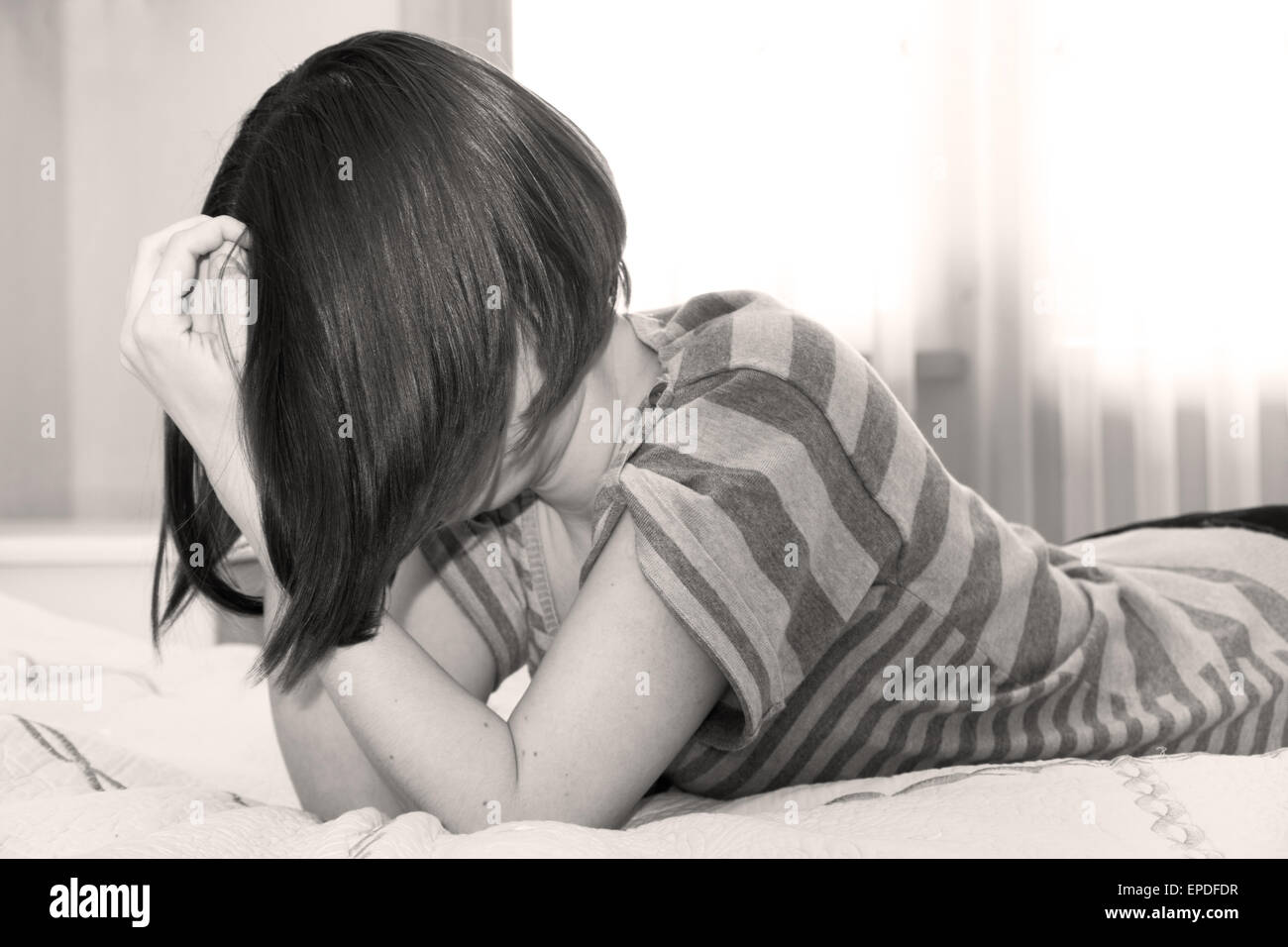 Young lonely depressed scared woman crying on the bed. Stock Photo