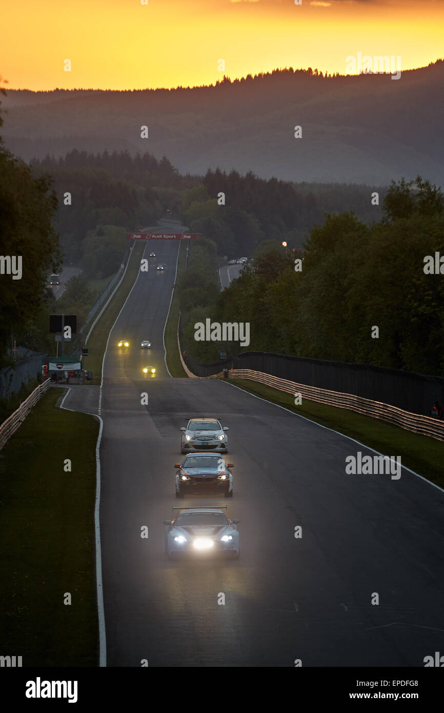 The field of racing cars drive in action on the ractetrack at sunset ...