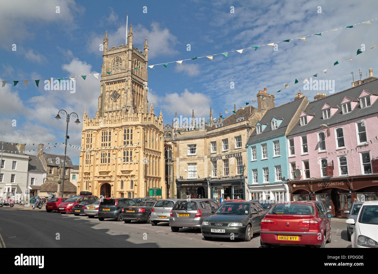 The Church of St John the Baptist and the colourful buildings on Market Place, Cirencester, Gloucestershire, UK. Stock Photo