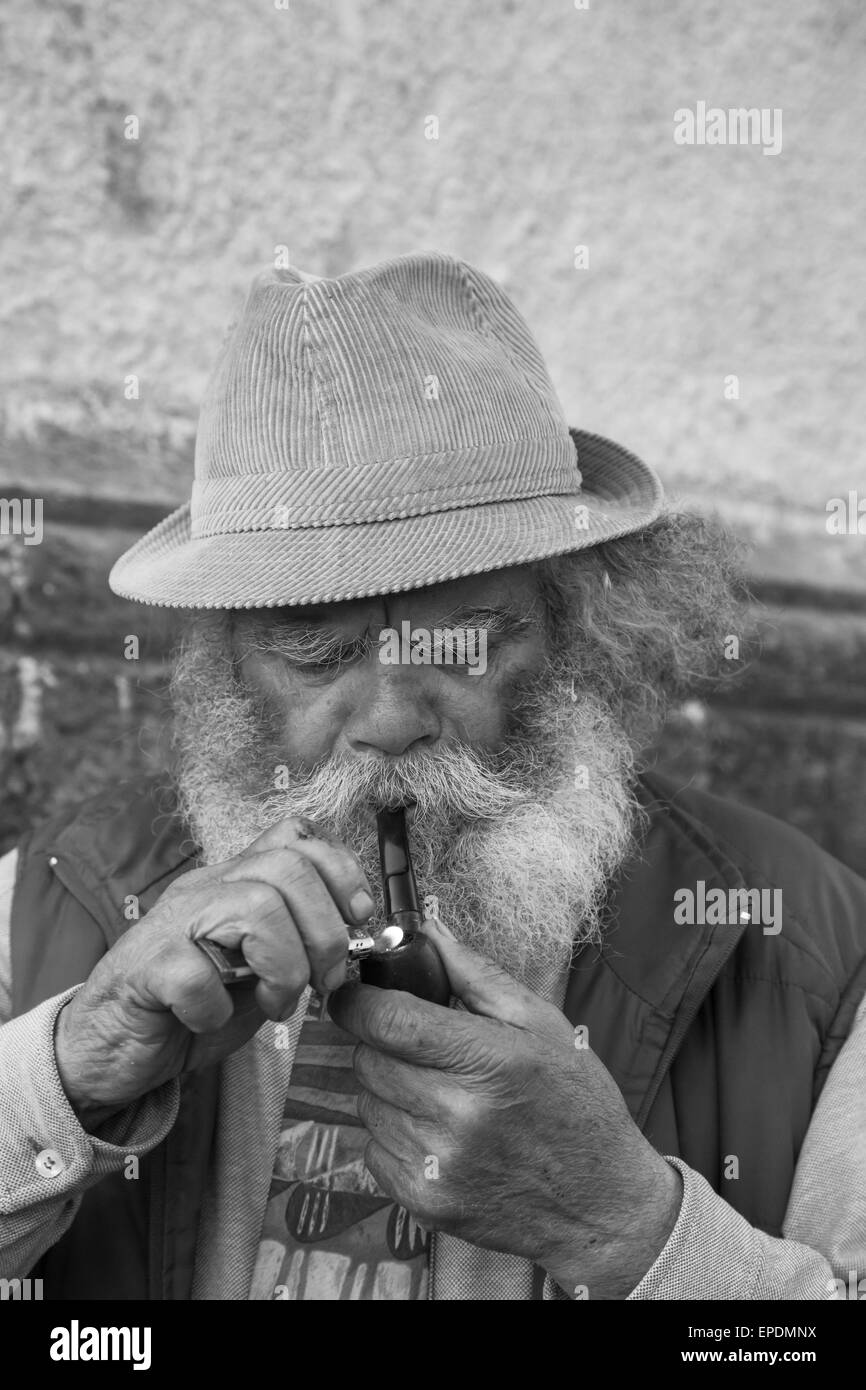 old man with a long white beard smokes a pipe Stock Photo
