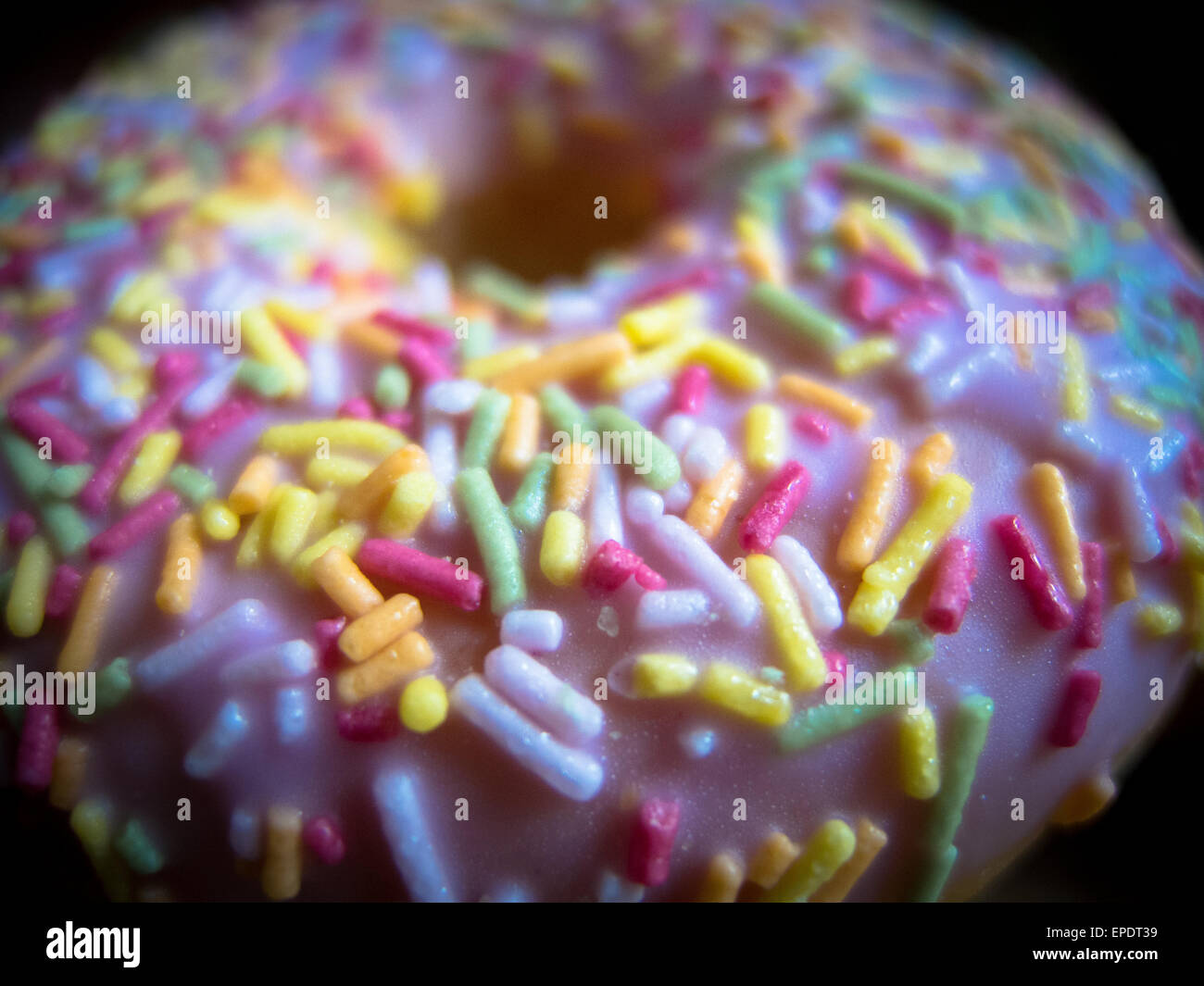 Closeup on a strawberry doughnut with pink icing and multi coloured sprinkles Stock Photo