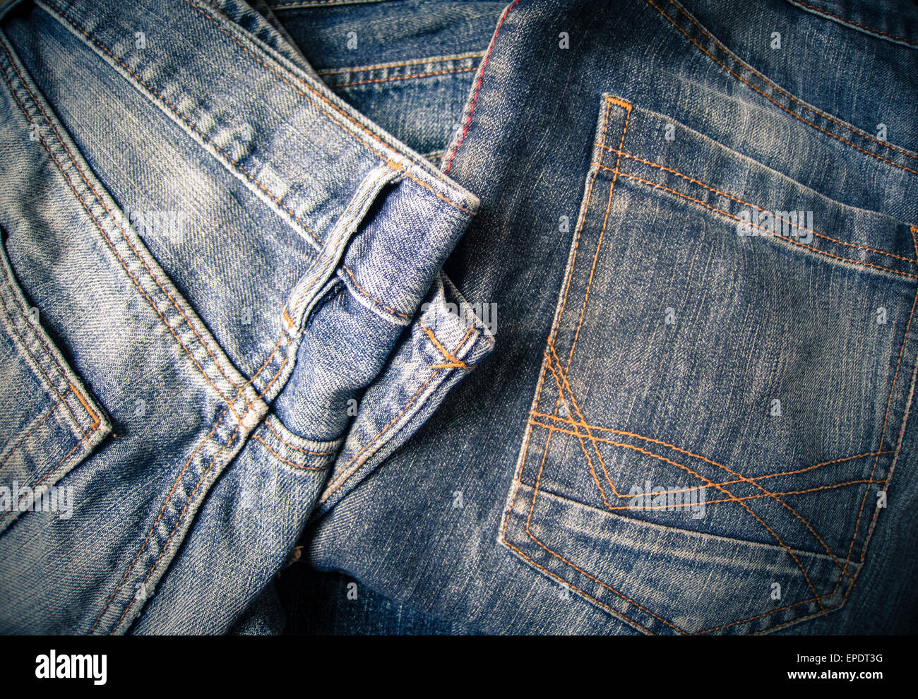 Old pairs of blue denim jeans with visible orange and red seams Stock Photo