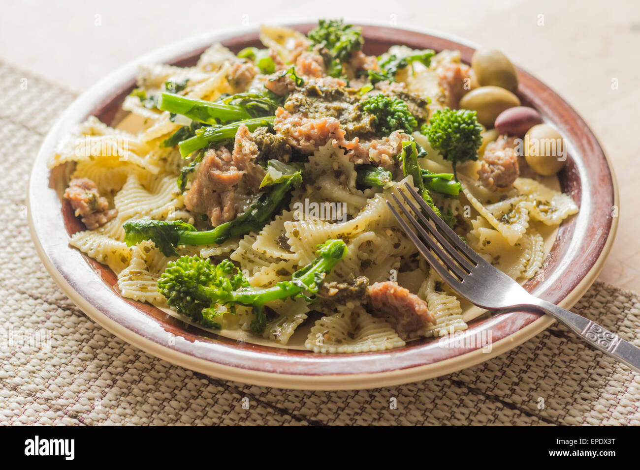 Bowtie pesto pasta with ground sausage and broccoli rabe garnished with
