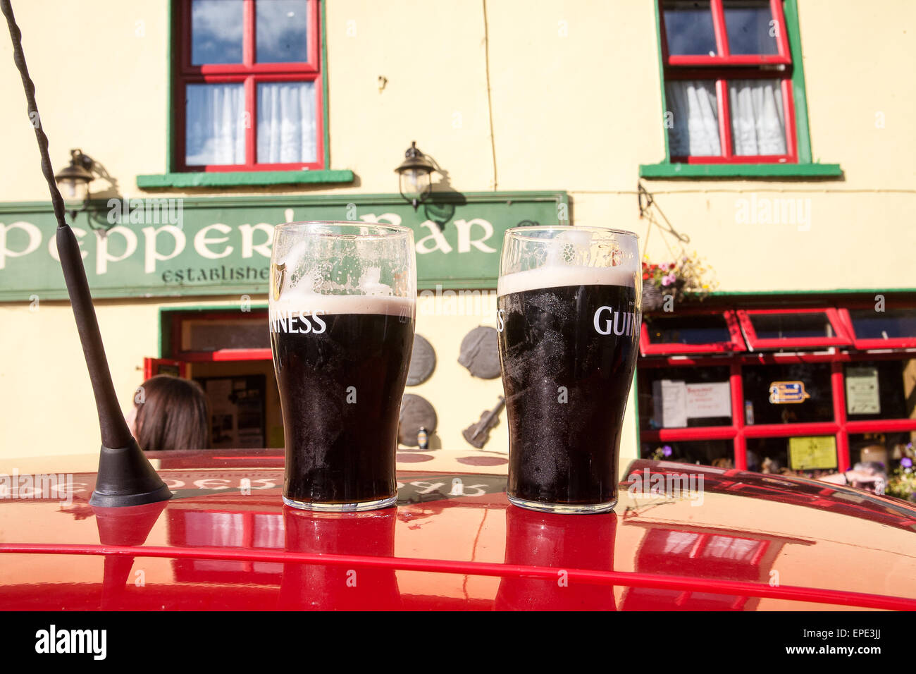 Two pints of guinness atop of car outside peppers bar hires stock
