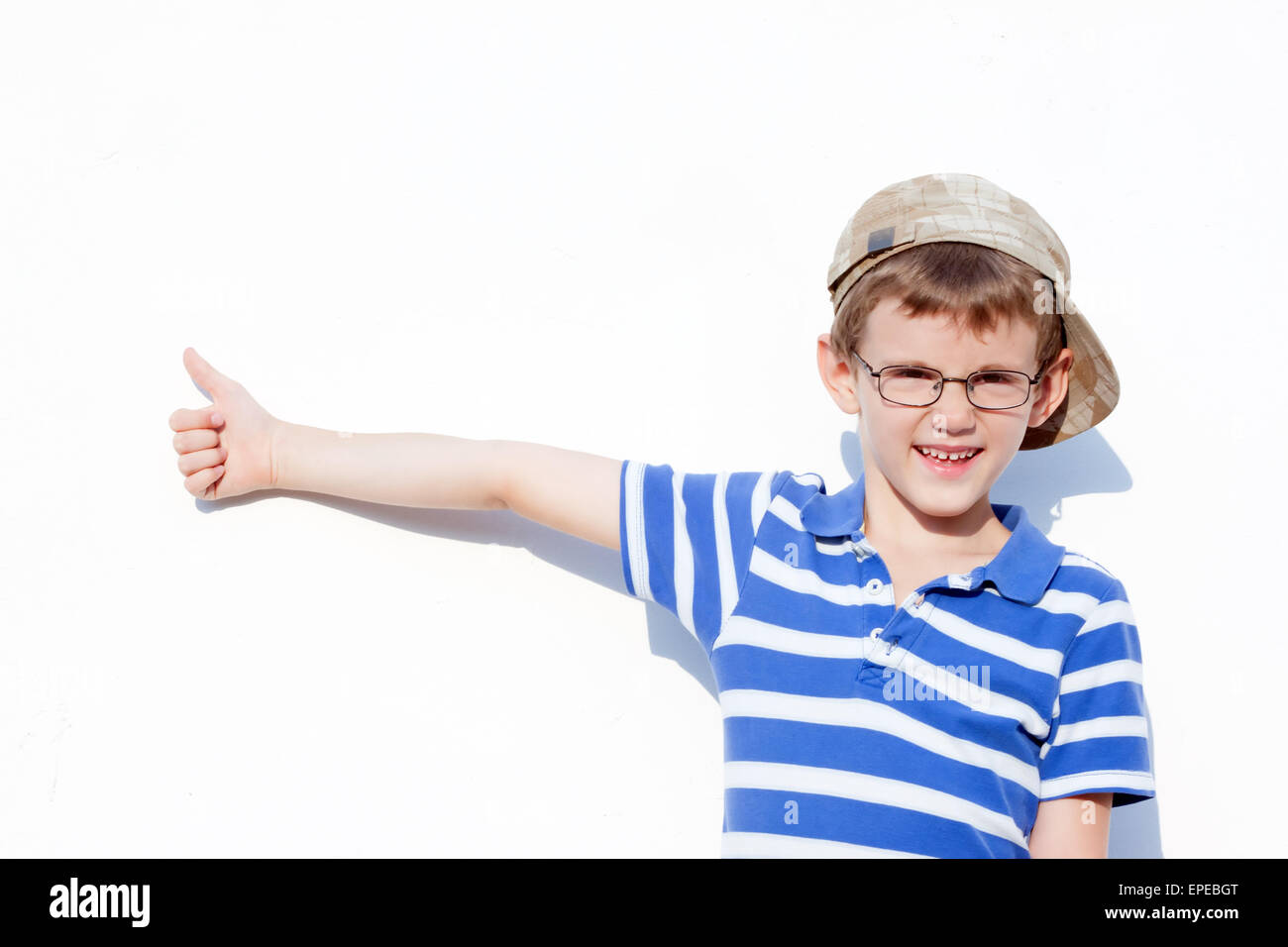 a little boy aged 6 to 8 years old with glasses and a cap showing a positive gesture.portrait Stock Photo