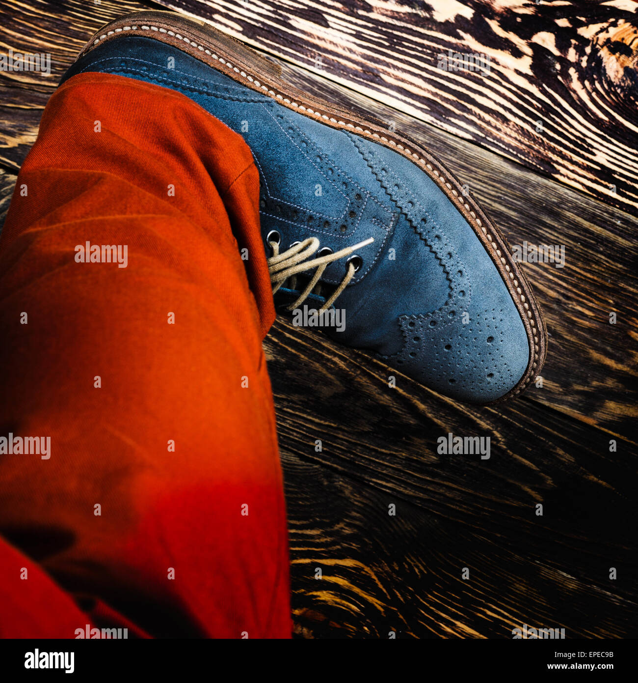 Close up of men's brogues (also known as derbies,gibsons or wingtips) made from blue oiled suede. Orange radiant pants and blue Stock Photo