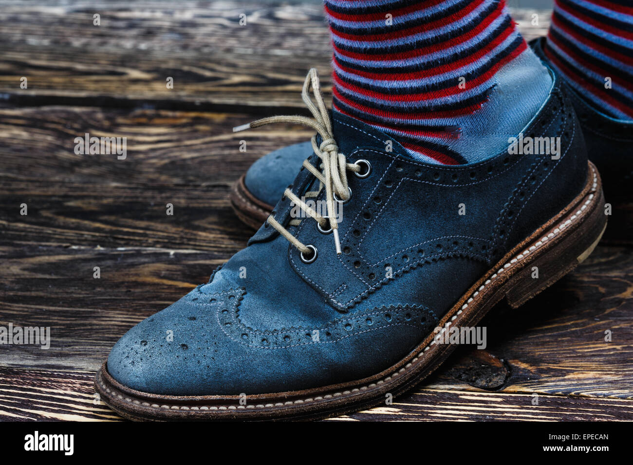 Close up of men's brogues (also known as derbies,gibsons or wingtips) made from blue oiled suede. Stripped socks are also shown Stock Photo