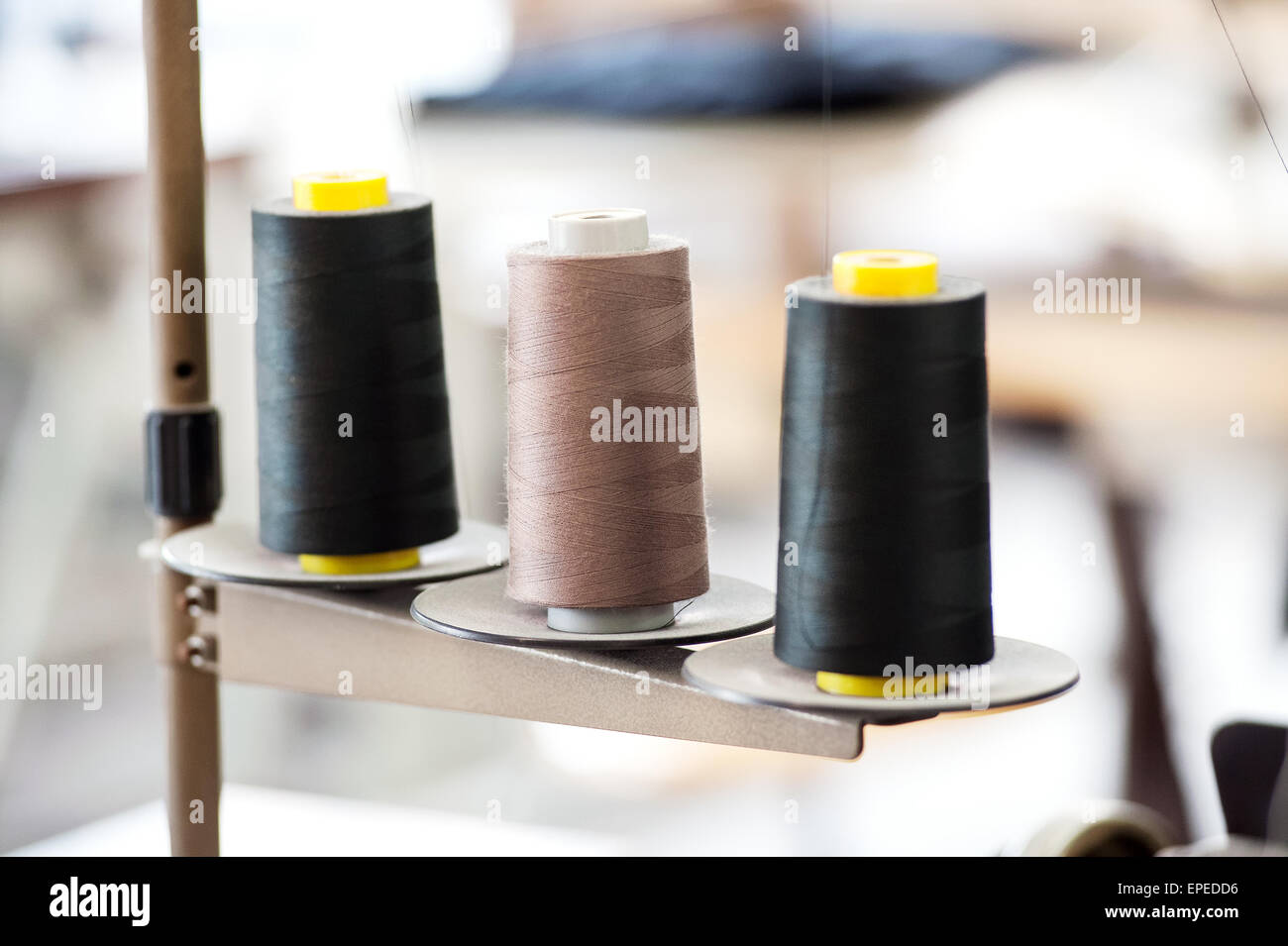 Three Industrial Spools of Thread in Black and Tan Colors in a Row in Manufacturing Setting Stock Photo