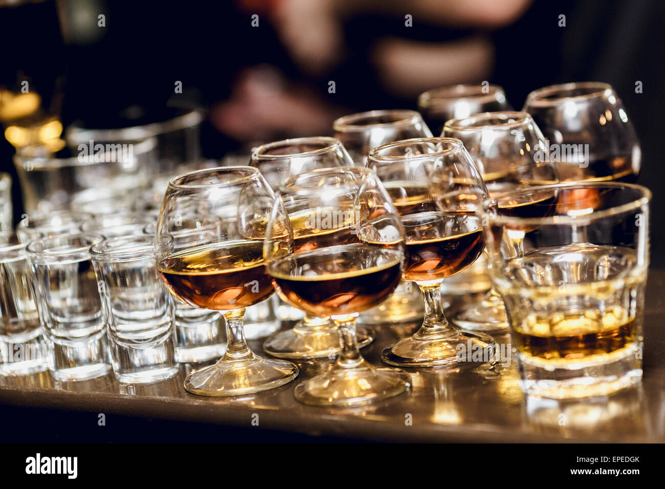 Various alcohol drinks standing on bar in snifters and shot glasses Stock Photo