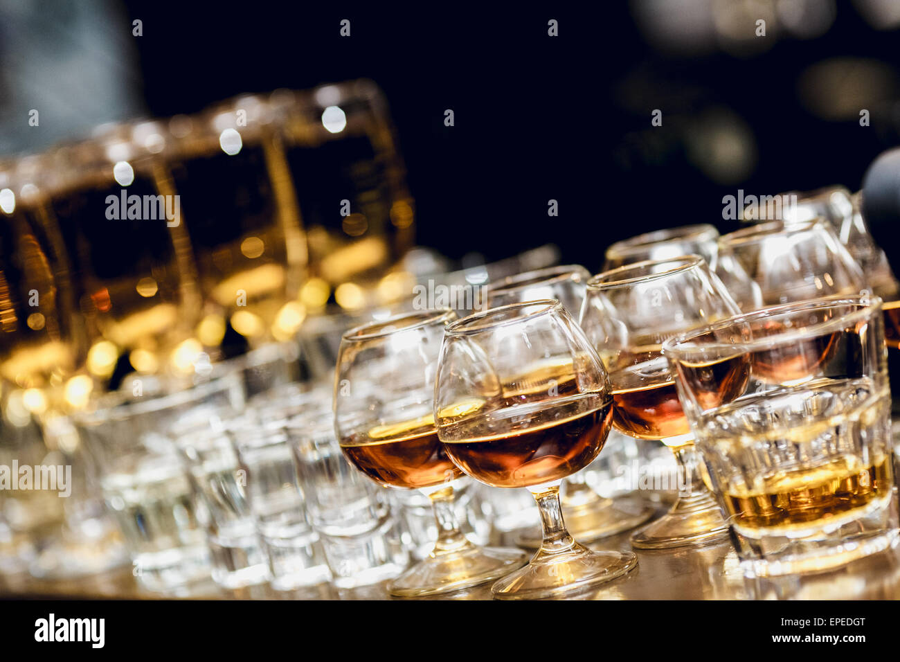 Various alcohol drinks standing on bar in snifters and shot glasses