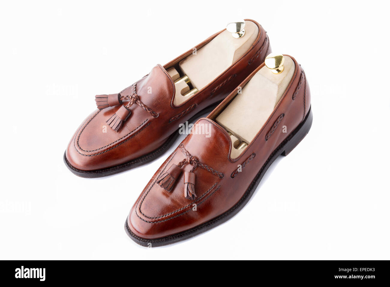 A pair of slightly worn, fine handcrafted tasseled vintage loafers with shoe trees inserted. Isolated on white background. Stock Photo