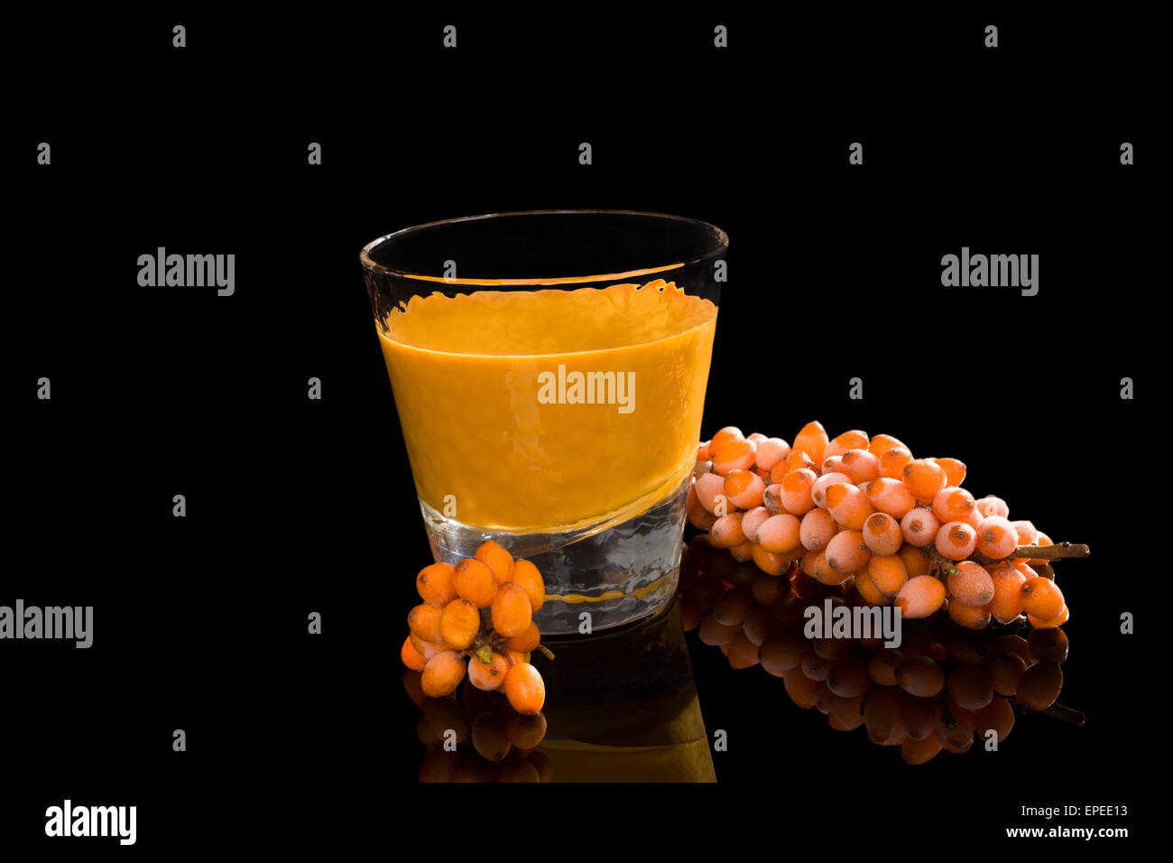 Sea buckthorn juice in glass with fresh fruits isolated on black background. Healthy living, alternative medicine, immune system Stock Photo