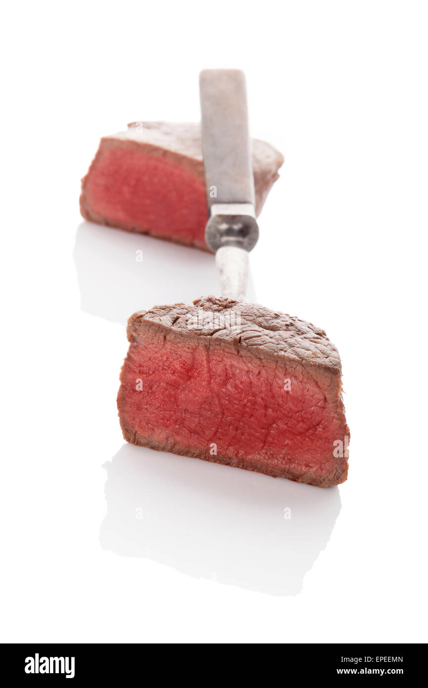 Delicious rare steak mignon on fork isolated on white background. Culinary beefsteak eating. Stock Photo