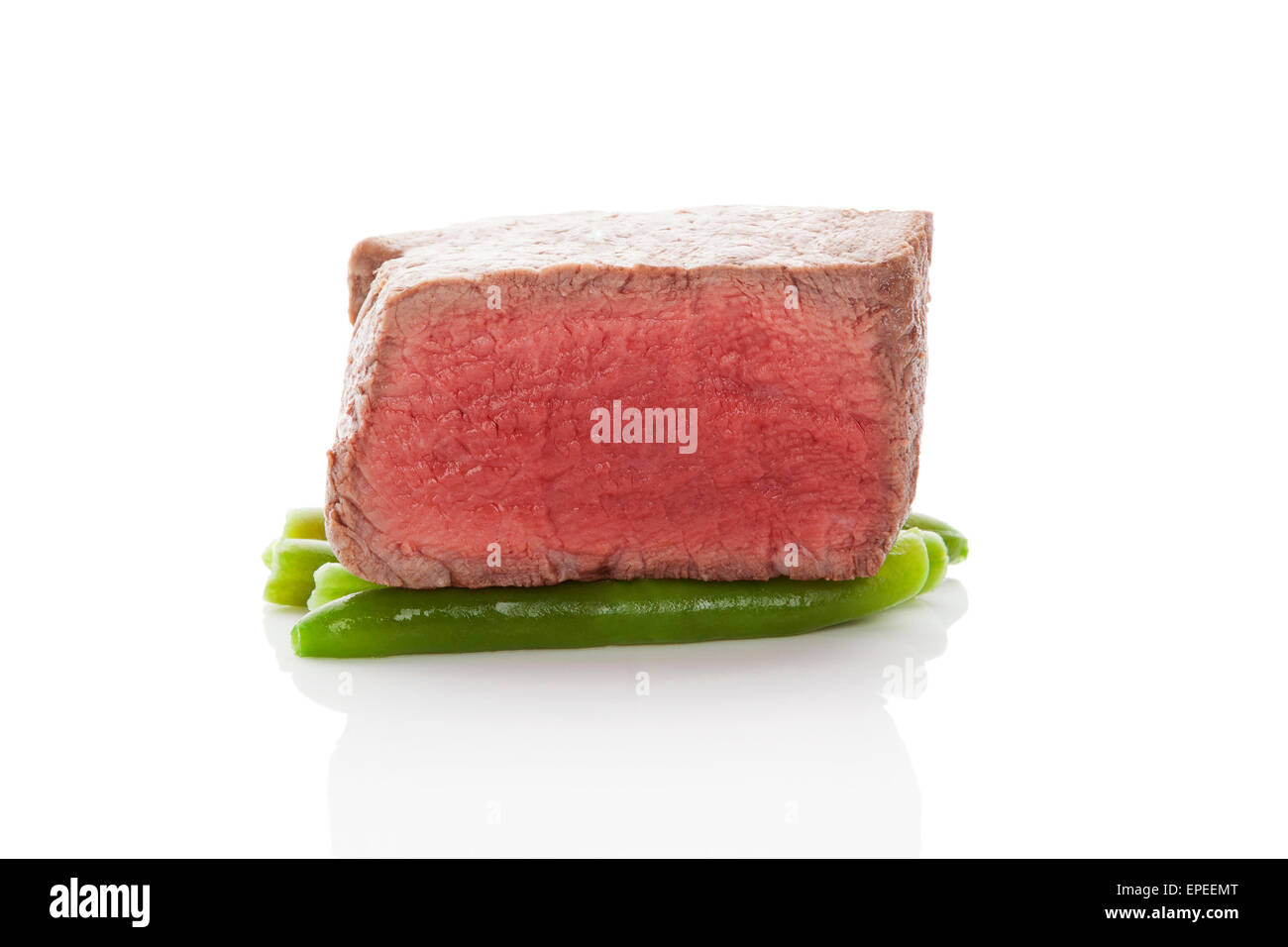 Beefsteak. Big sirloin steak on green beans isolated on white background. Culinary red meat steak eating. Stock Photo