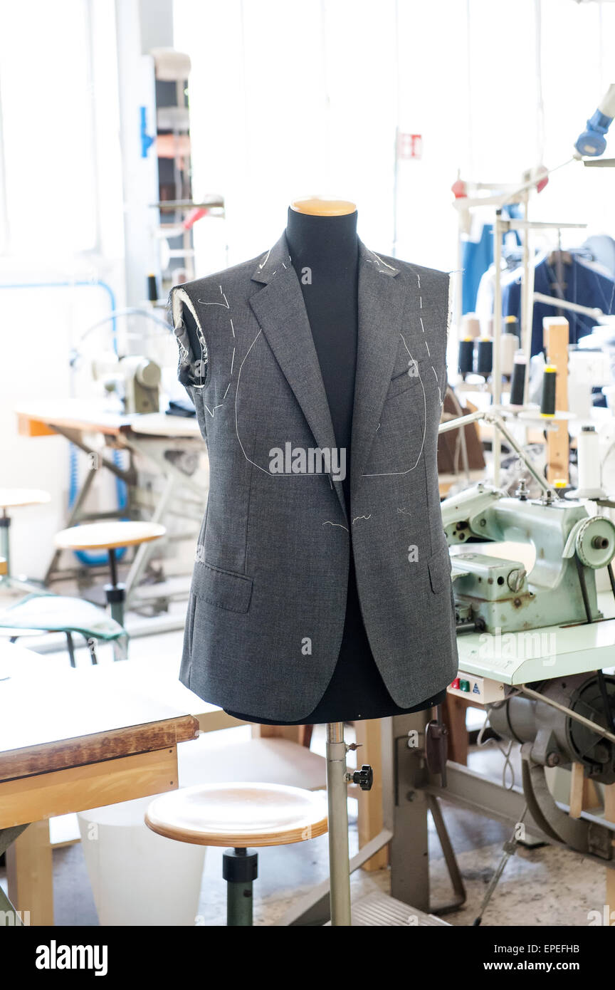 Working on a handmade jacket displayed on a mannequin ready for the fitting of the sleeves in the interior of a tailors shop Stock Photo