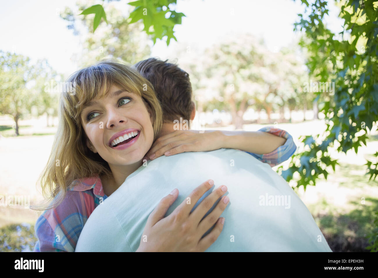 Pretty blonde smiling in a park while hugging boyfriend Stock Photo - Alamy