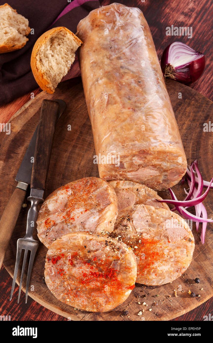 Head cheese cold cut vintage background. Brawn with onion and bread on