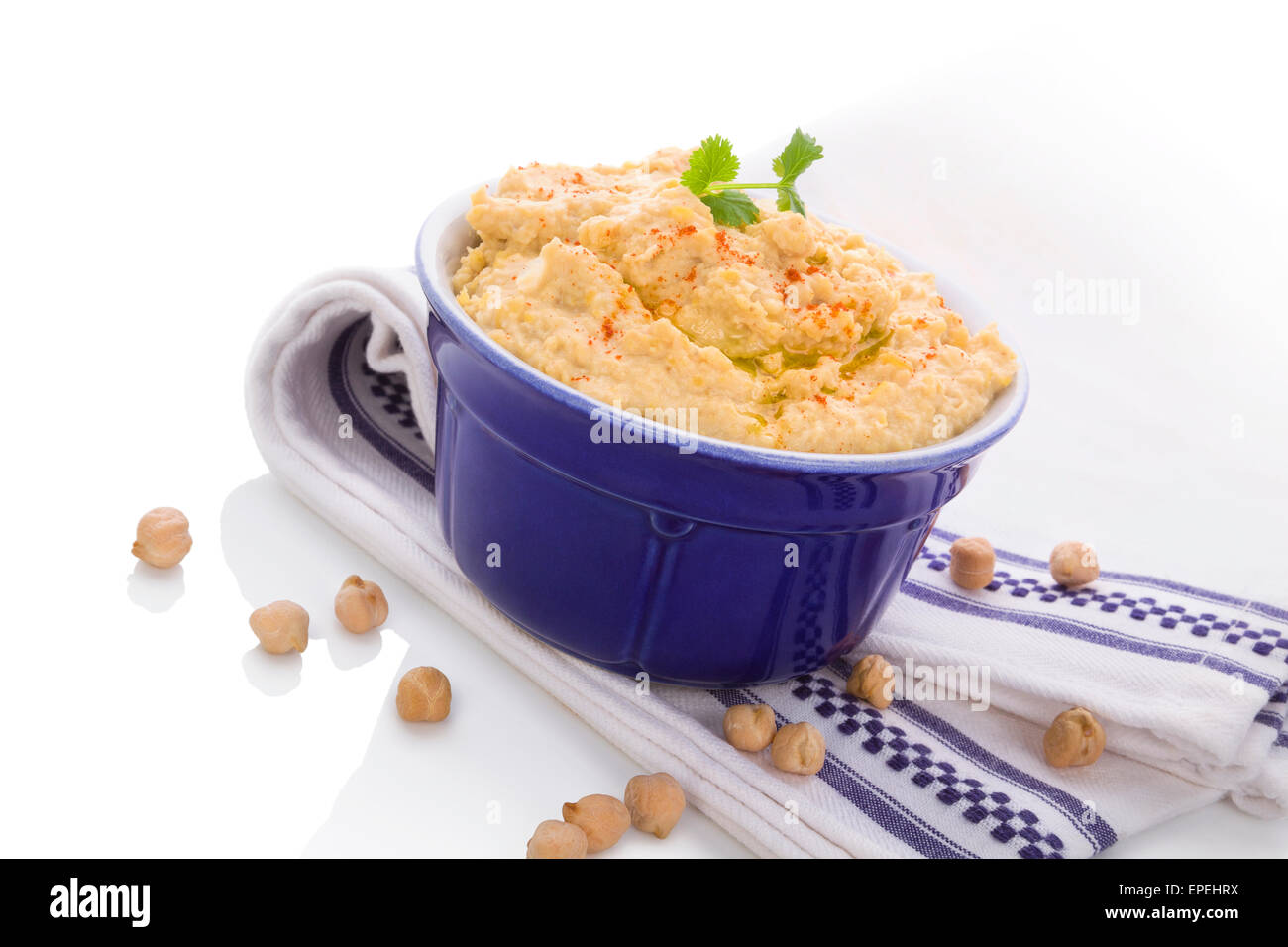 Delicious hummus in ceramic pot on white and blue table cloth isolated on white background. Traditional eastern eating. Stock Photo