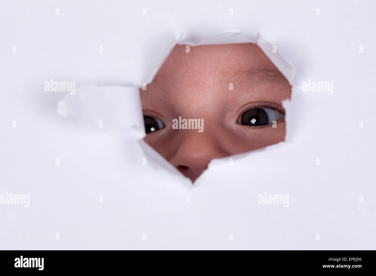 Baby ist neugierig und schaut durch ein Loch Stock Photo